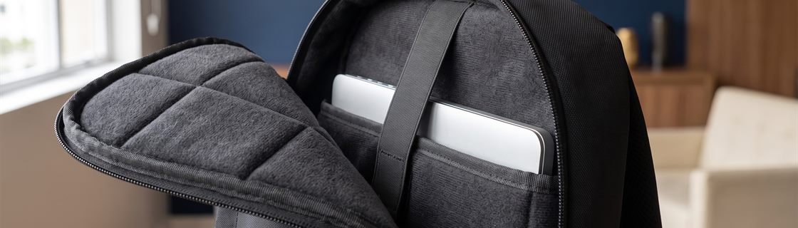 Close-up do compartimento acolchoado de uma mochila corporativa para notebook, com o forro interno à vista e um notebook entrando no compartimento